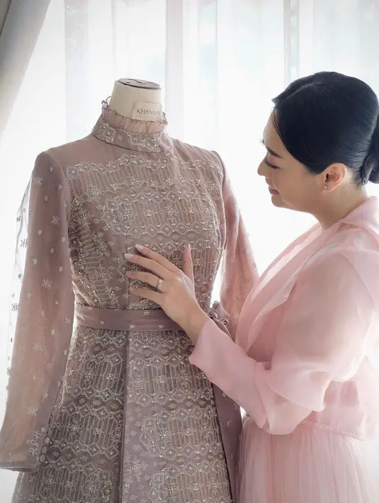 Pada acara resepsi kedua, Rizka mengenakan dress nuansa mauve lansiran brand lokal Khanaan.