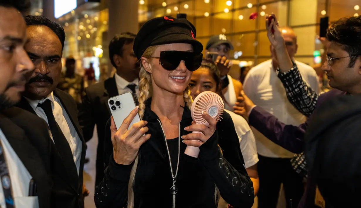 Selebritas Amerika Serikat Paris Hilton dikawal oleh petugas keamanan saat tiba di Bandara Internasional Chhatrapati Shivaji, Mumbai, India, 19 Oktober 2022. Paris memilih kacamata hitam dan topi trendi untuk melengkapi penampilannya. (AP Photo/Rafiq Maqbool)