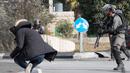 Seorang pria Palestina terjatuh usai ditembak dari jarak dekat oleh polisi Israel di dekat Ramallah, Tepi Barat, Jumat (15/12). Pemuda ini ditembak usai menikam tentara perbatasan Israel. (AFP Photo/Oren Ziv)