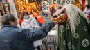 Seorang pria memberikan uang kepada penari singa setelah tampil pada pekan raya akhir tahun di Distrik Nihonbashi, Tokyo, Jepang, 26 Desember 2022. Tak hanya menyuguhkan pemandangan indah dan makanan yang lezat, Jepang juga menjadi negara yang tepat untuk merayakan tahun baru. (Yuichi YAMAZAKI/AFP)