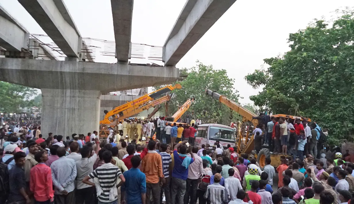 Petugas mengoperasikan alat berat di lokasi runtuhnya sebuah jalan layang di kota Varanasi, Selasa (15/5). Lokasi insiden pun menjadi tontonan warga sekitar yang berkerumun ingin menyaksikan karena penasaran. (AP Photo)
