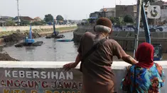 Warga menyaksikan proses pengerukan endapan tanah di aliran Sungai Ciliwung, Jakarta, Selasa (28/7/2020). Pengerukan endapan ini untuk memperlancar aliran air Sungai Ciliwung serta upaya pencegahan banjir saat musim hujan. (Liputan6.com/Helmi Fithriansyah)