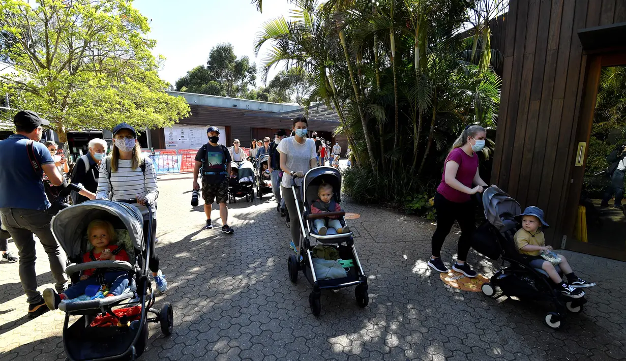 Keluarga memasuki Kebun Binatang Taronga di Sydney (18/10/2021). Kebun binatang Taronga membuka kembali pintunya bagi pengunjung yang divaksinasi setelah pencabutan pembatasan penguncian Sydney. (AFP/Saeed Khan)