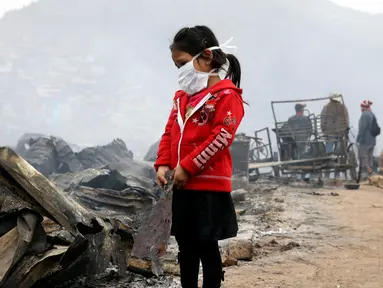 Seorang anak berdiri di lokasi kebakaran besar yang melanda permukiman Cantagallo di Lima, Peru, Jumat (4/11). Dilaporkan, permukiman yang terbakar itu dihuni oleh komunitas Suku Amazon yang tinggal di Lima. (REUTERS/Guadalupe Pardo)