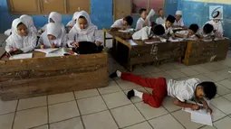 Murid-murid kelas V melakukan kegiatan belajar pada meja yang diubah menjadi kursi dan tempat belajar di SDN Kertajaya 2, Rumpin, Bogor (22/7/2019). Sudah lebih dari tiga tahun mereka belajar  pada fasilitas yang minim. (merdeka.com/Arie Basuki)