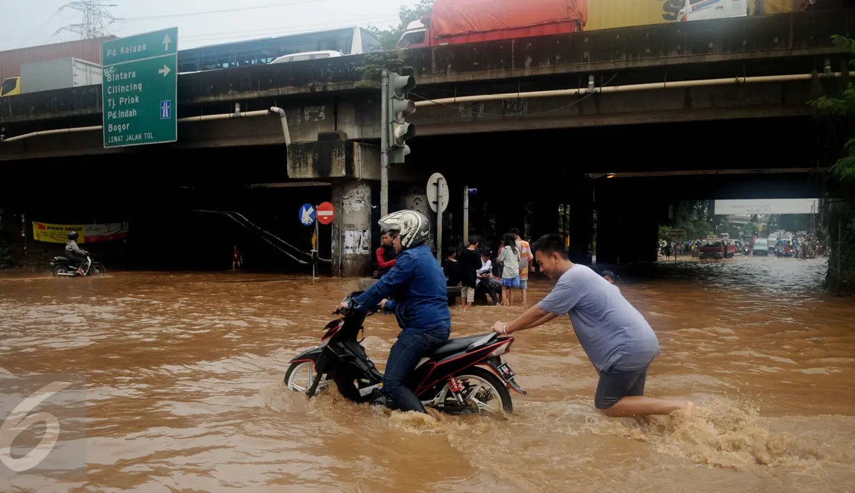 Warga membantu mendorong motor yang mogok saat berusaha menerobos banjir di Jalan Raya Kalimalang, Caman, Bekasi, Senin (20/2). Banjir setinggi 80 cm itu disebabkan drainase buruk & diperparah tingginya intensitas curah hujan (Liputan6.com/Gempur M Surya)