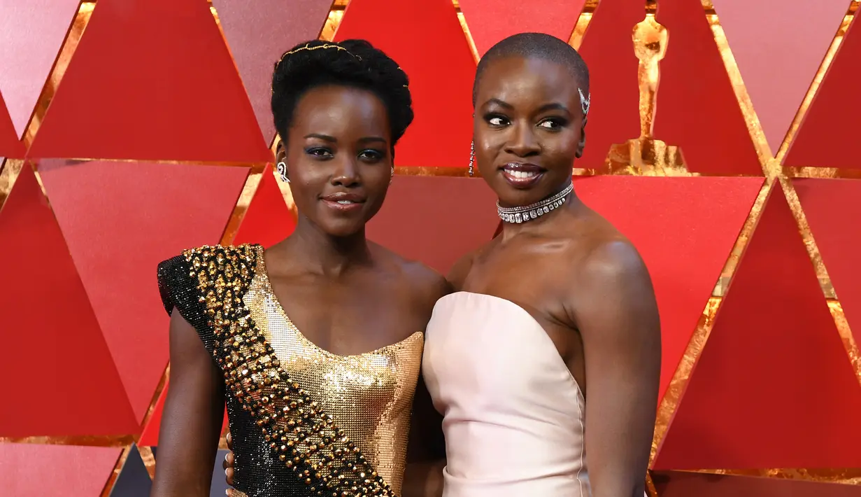 Aktris Kenya, Lupita Nyong'o dan aktris AS, Danai Gurira berpose untuk fotografer di karpet merah ajang Piala Oscar 2018, Los Angeles, Minggu (4/3).  Dua pemain "Black Panther" tersebut adu cantik mengenakan gaun seksi dan elegan. (ANGELA WEISS / AFP)