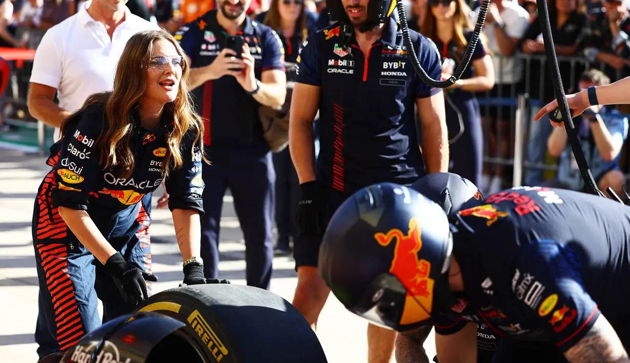 Aktris Amerika Serikat, Drew Barrymore menjajal mengganti ban saat berkunjung ke paddock tim Red Bull Racing menjelang Formula 1 GP Amerika Serikat 2023 di Circuit of The Americas, Austin, Texas, Kamis (19/10/2023) waktu setempat. (AFP/Mark Thompson)