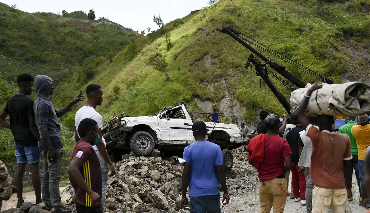Sebuah derek memindahkan truk dari tumpukan batu setelah tanah longsor yang dipicu oleh gempa berkekuatan 7,2 yang melanda empat hari sebelumnya di River Glass, Haiti, Rabu (18/8/2021). Korban jiwa akibat gempa di Haiti Sabtu pekan lalu terus bertambah menjadi 1.941 orang.  (AP/Matias Delacroix)