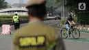Petugas gabungan melakukan pengalihan jalur pesepeda di kawasan Sudirman-Thamrin, Jakarta, Minggu (5/9/2021). Pemberlakuan jalur ganjil genap pada masa PPKM membuat pengguna sepeda dilarang melintasi kawasan ganjil-genap pagi ini. (Liputan6.com/Angga Yuniar)