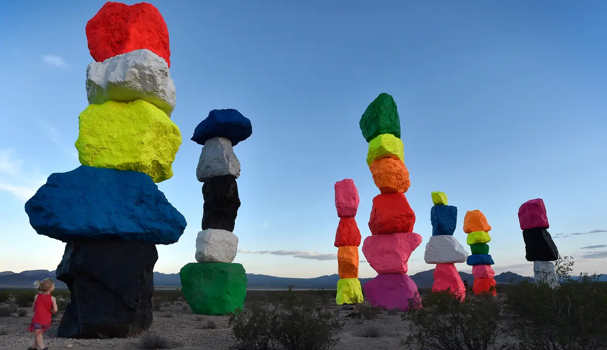 Seorang bocah memandangi instalasi seni yang berjudul ' Seven Magic Mountains' yang dibuat oleh seniman Swiss Ugo Rondinone di dekat Jean , Nevada, 14 Mei 2016. Karya seni berupa menara yang terbentuk dari tumpukan batu yang indah. (David Becker / AFP)