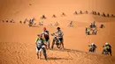 Para pebalap mengendarai sepeda melintasi sepanjang bukit pasir pada etape 1 edisi ke 14 balap sepeda gunung Titan Gurun 2019 di sekitar Kota Merzouga, Maroko, Minggu (28/4/2019). Trek Titan Gurun 2019 sepanjang 640 km menghubungkan antara Merzouga dan Maadid. (Franck Fife / AFP)