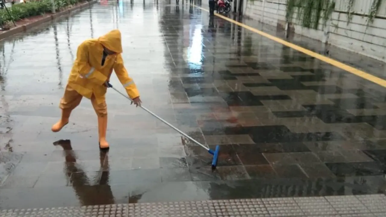 Petugas tengah membersihkan genangan air di depan Stasiun Senayan. (Twitter MRT Jakarta @mrtjakarta)
