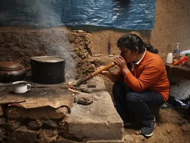 Calon ibu negara Peru, Lilia Paredes (48) meniupkan buluh bambu untuk menyalakan api di rumahnya yang terbuat dari batu bata di pedesaan Chugur, 22 Juli 2021. Suaminya, Pedro Castillo yang merupakan mantan guru dan pemimpin serikat pekerja memenangkan pemilihan presiden Peru. (AP/Franklin Briceno)