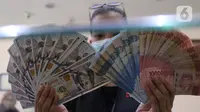 Petugas menunjukkan uang rupiah di penukaran uang, Jakarta, Senin (9/11/2020). ). Nilai tukar rupiah terhadap dolar AS bergerak menguat pada perdagangan di awal pekan ini Salah satu sentimen pendorong penguatan rupiah kali ini adalah kemenangan Joe Biden atas Donald Trump. (Liputan6.com/Angga Yuniar