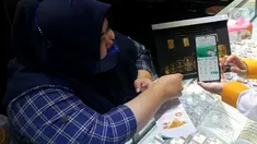Pegawai PT Bank Syariah Indonesia Tbk (BSI) Cabang Mayestik memberikan penjelasan fitur gadai dan cicil emas di salah satu kios saat Grebek Pasar BSI di Pasar Mayestik, Jakarta (16/12/2021). BSI dorong pertumbuhan pembiayaan gadai dan cicil emas lewat program grebek pasar. (Liputan6.com/HO/Rizky)