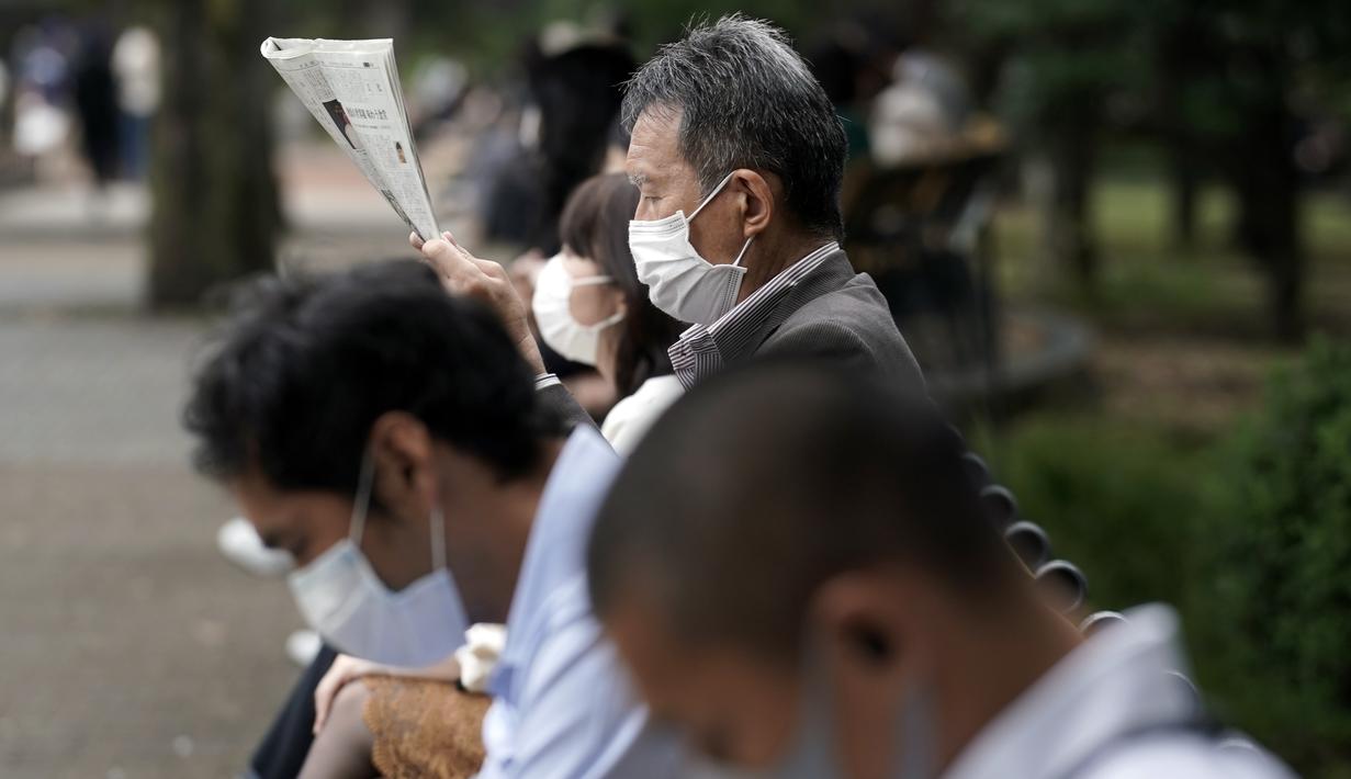 Orang-orang yang mengenakan masker pelindung untuk membantu mengekang penyebaran virus corona beristirahat di sebuah taman Rabu, Jepang (14/10/2020). Tokyo mengonfirmasi lebih dari 170 kasus virus corona baru pada hari Rabu. (AP Photo/Eugene Hoshiko)