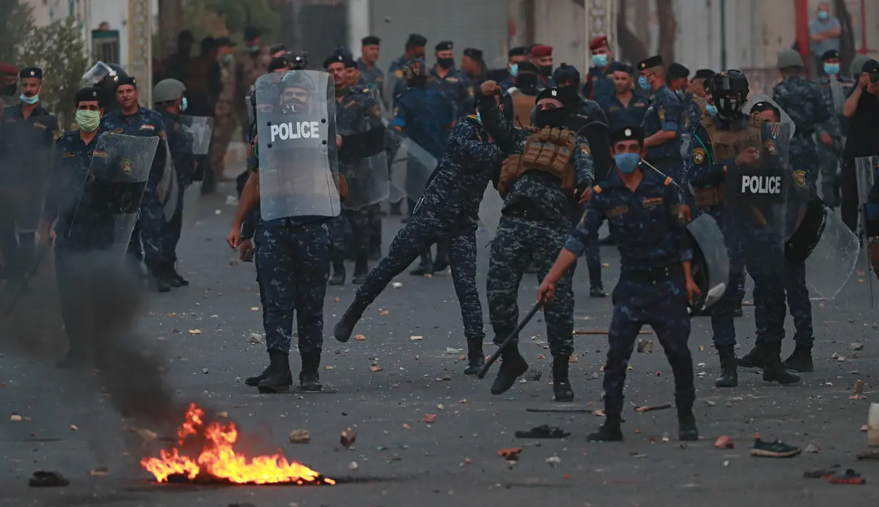 Pasukan keamanan berusaha membubarkan para demonstran saat protes antipemerintah di dekat Alun-Alun Tahrir, Baghdad, Irak, Senin (27/7/2020). Perdana Menteri Irak mengatakan telah memerintahkan penyelidikan atas pembunuhan dua demonstran antipemerintah. (AP Photo/Hadi Mizban)