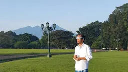 Dengan mengenakan kemeja putih dan sarung kotak-kotak berwarna biru, Jokowi tampak santai menyaksikan gerhana matahari di halaman Istana Bogor, Rabu (9/3). (facebook.com/Jokowi)