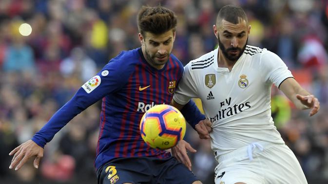Bek Barcelona, Gerard Pique, berebut bola dengan striker Real Madrid, Karim Benzema, pada laga La Liga Spanyol di Stadion Camp Nou, Barcelona, Minggu (28/10). Barcelona menang 5-1 atas Madrid. (AFP/Lluis Gene)