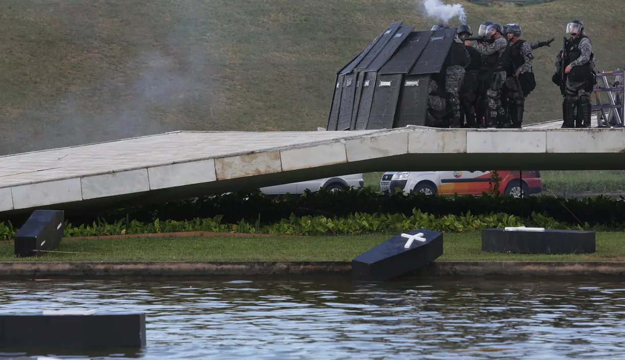 Petugas keamanan setempat membentuk barikade untuk menghalau para demonstran di gedung Kongres Nasional di Brasilia, Brasil (25/4). Dalam bentrok ini petugas menembakan gas air mata untuk membubarkan para demonstran. (AP Photo/Eraldo Peres)
