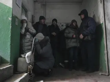 Orang-orang berlindung dari penembakan di dalam pintu masuk gedung apartemen di Mariupol, Ukraina, Minggu, 13 Maret 2022. Pada 24 Februari 2022, Rusia melancarkan invasi berskala besar ke Ukraina, salah satu negara tetangganya di sebelah barat daya. (AP Photo/Evgeniy Maloletka)