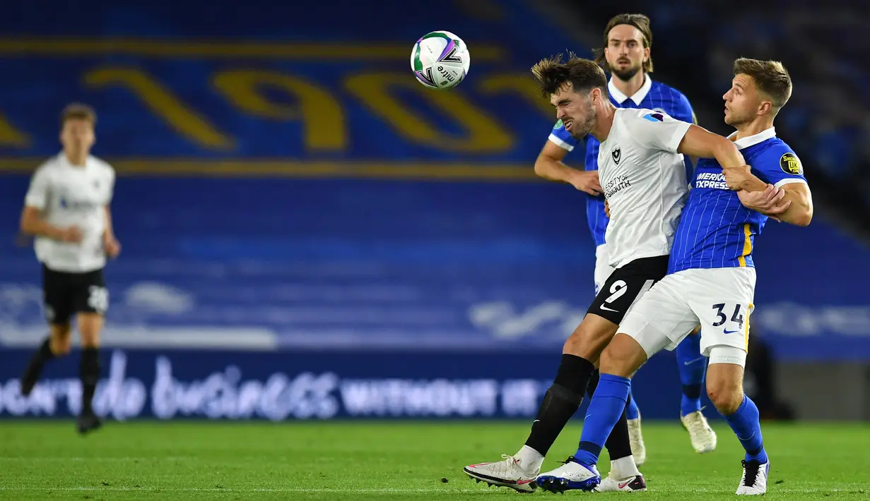 Bek Brighton, Joel Veltman, berebut bola dengan striker Portsmouth, John Marquis, pada laga Piala Inggris di Falmer Stadium, Jumat (18/9/2020) dini hari WIB. Brighton menang 4-0 atas Portsmouth. (AFP/Glyn Kirk/pool)