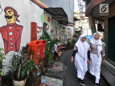 Anak sekolah melintas di depan lukisan tembok atau mural yang menghiasi gang di RT 13 RW 06, Jembatan Lima, Jakarta, Kamis (10/1). Warna-warni mural di pemukiman padat penduduk itu merupakan ide Aryanto selaku Ketua RT 13. (Merdeka.com/Iqbal Nugroho)