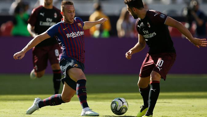 Gelandang Barcelona Arthur Melo berusaha melewati pemian AC Milan Hakan Calhanoglu saat bertanding pada International Champions Cup di Levi's Stadium di Santa Clara, California (4/8). Milan menang tipis 1-0 atas Barcelona. (AFP Photo/Lachlan Cunningham)