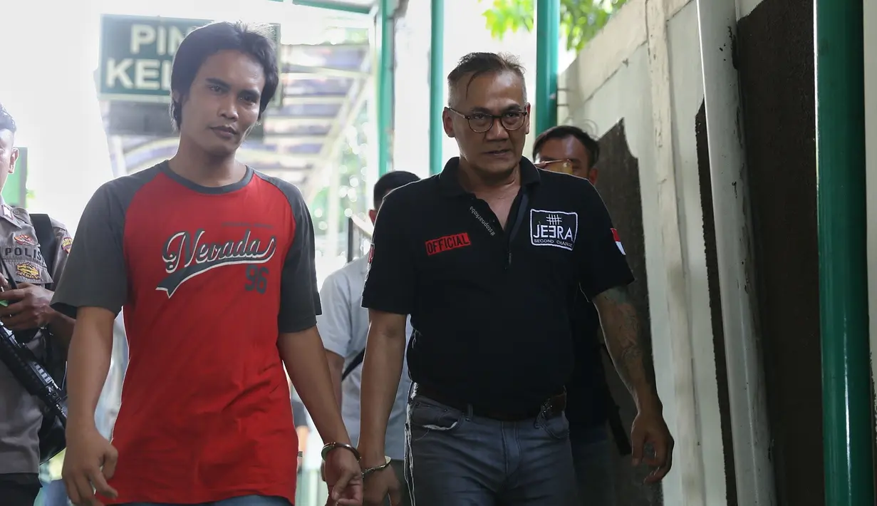 Tio datang bersama tahanan lain saat memasuki kantor pengadilan. Bintang film Filosofi Kopi 2: Ben & Jody itu datang mengenakan kaos polo shirt warna hitam. (Nurwahyunan/Bintang.com)