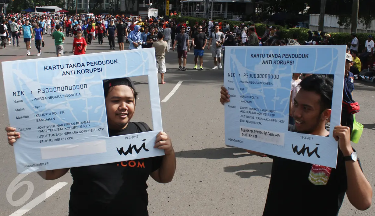 Dua orang pria berpose dengan papan mirip E-KTP di CFD, Jakarta, Minggu (19/3). Aktivis Gerakan Sapu Koruptor menuntut penegak hukum untuk segera menuntaskan kasus korupsi E-KTP. (Liputan6.com/Angga Yuniar) 