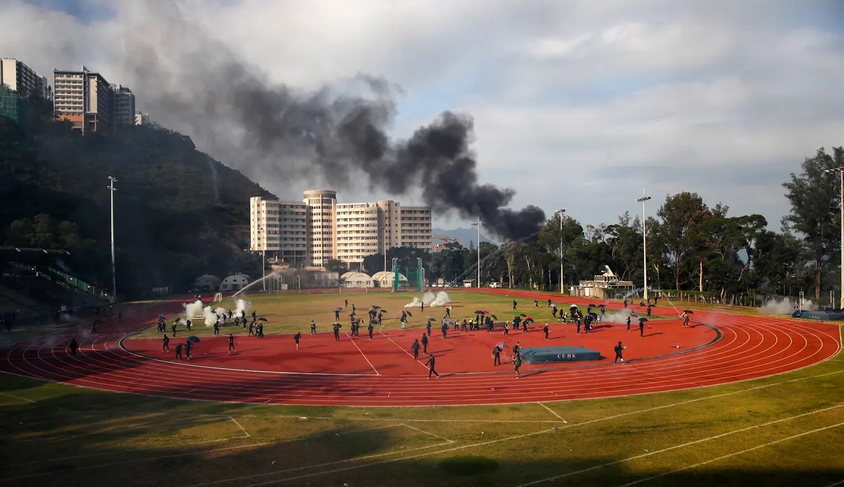Para pelajar berusaha membersihkan tabung gas air mata dari lapangan saat terjadi bentrok dengan polisi di Chinese University, Hong Kong, Selasa (12/11/2019). Gerakan antipemerintah Hong Kong yang telah berlangsung selama lima bulan bertindak semakin keras. (AP Photo)
