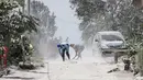 Warga mengenakan masker membersihkan jalan yang tertutup abu vulkanik Gunung Sinabung di Karo, Sumatra Utara (20/2). Gunung Sinabung meletus kembali tanggal 19 Februari, yang mengeluarkan asap tebal setinggi 5.000 meter. (AFP Photo/Kadri Boy Tarigan)