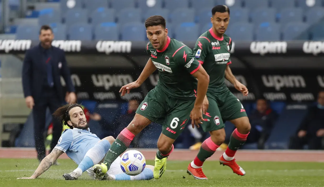 Bek Crotone, Lisandro Magallan (tengah) memenangi perebutan bola dengan gelandang Lazio, Luis Alberto dalam laga lanjutan Liga Italia 2020/2021 pekan ke-27 di Olimpico Stadium, Roma, Jumat (12/3/2021). Crotone kalah 2-3 dari Lazio. (AP/Alessandra Tarantino)