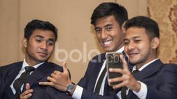 Pemain Timnas Indonesia U-22, Gian Zola, Hanif Sjahbandi (tengah) dan Asnawi Mangkualam (kiri), melakukan selfie. Dengan memakai pakaian ini Timnas U-22 diharapkan bisa tampil lebih elegan membawa citra bangsa. (Bola.com/Vitalis Yogi Trisna)