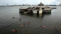 Sejumlah anak bermain di dekat Masjid yang terkena Abrasi di kawasan Muara Baru, Jakarta, Kamis (4/1). Sebagian anak-anak yang bermukim di kawasan tersebut banyak menghabiskan waktu saat berlibur sekolah untuk bermain di laut. (Liputan6.com/Johan Tallo)