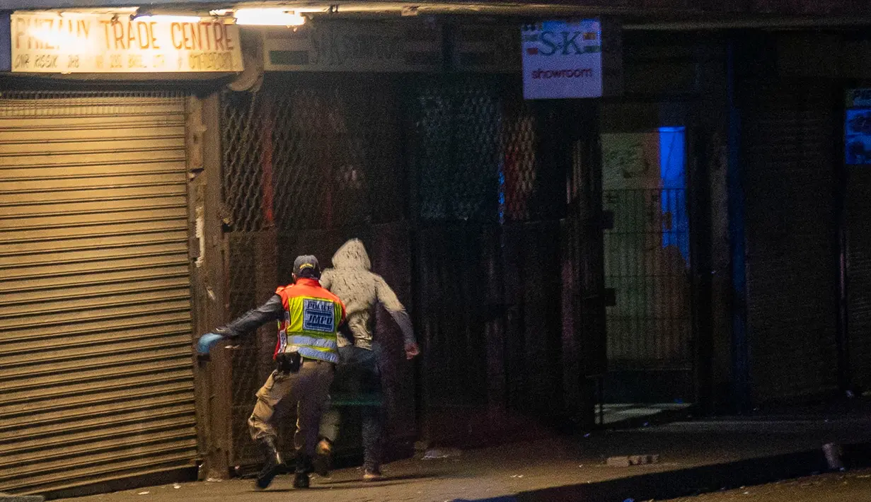 Afrika Selatan Lockdown 21 Hari: Polisi mengejar seorang pria saat berpatroli di pusat kota Johannesburg, Afrika Selatan, Jumat (27/3/2020). Polisi dan tentara mulai berpatroli beberapa saat setelah Afrika Selatan melakukan Lockdown 21 Hari  untuk mengurangi penyebaran Covid-19. (AP//Jerome Delay)