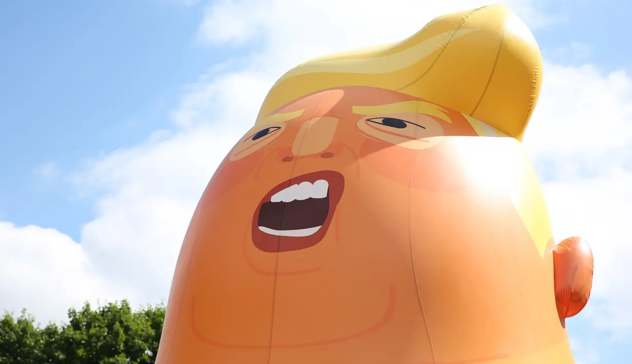 Aktivis mengembangkan balon berbentuk bayi Presiden AS Donald Trump di London, 10 Juli 2018. Balon raksasa itu menggambarkan Presiden AS Donald Trump sebagai bayi berwarna oranye yang mengenakan popok dan dalam keadaan marah. (AFP/Isabel INFANTES)