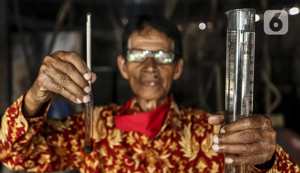 Seorang pria menunjukkan alkohol tradisional di industri rumahan Desa Bekonang, Kecamatan Mojolaban, Kabupaten Sukoharjo, Jawa Tengah, Rabu (18/11/2020). Penyulingan dan penyaringan akan menghasilkan minuman yang jernih, nyaris tampak seperti air.  (Liputan6.com/Johan Tallo)