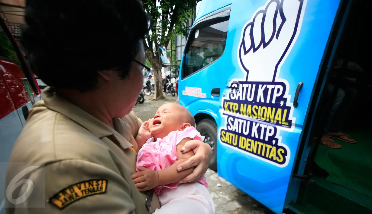 Seorang petugas dinas kependudukan menggendong balita saat orang tuanya menjalanai pendataan kependudukan di Asrama Haji Donohudan ,Boyolali, Jawa Tengah, (25/1). (Boy Harjanto)