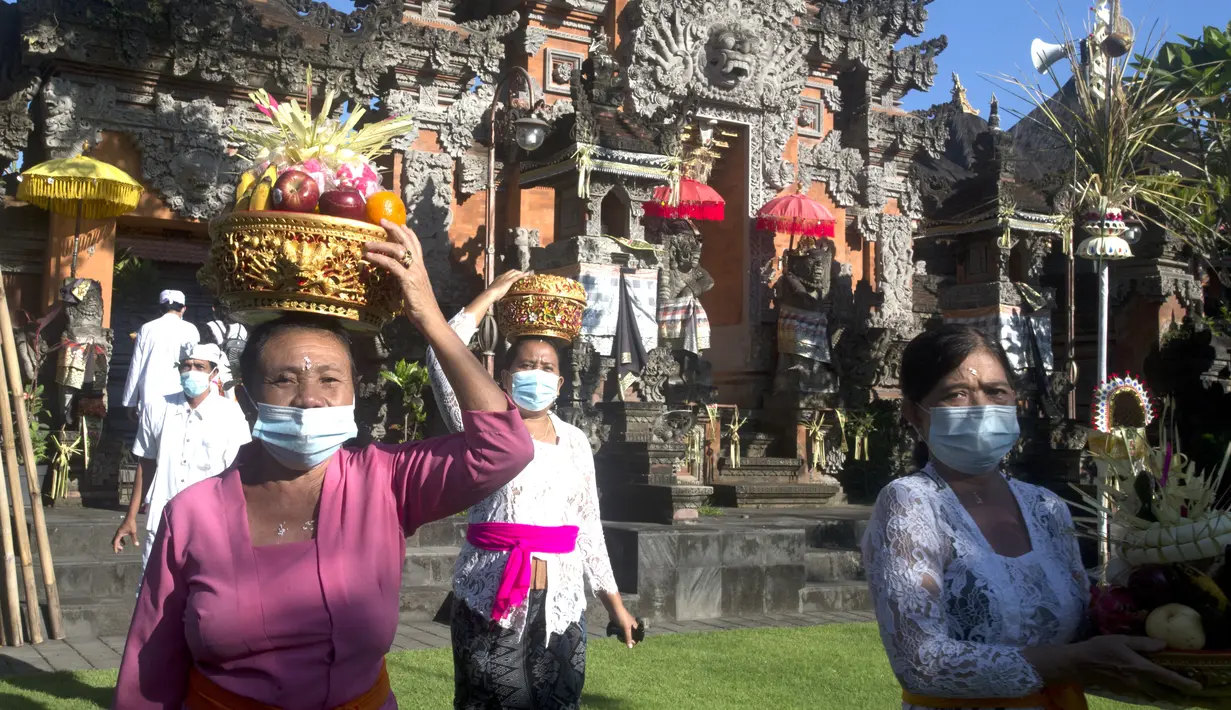 Umat Hindu membawa sesajen saat Hari Raya Galungan di sebuah pura di Bali, Rabu (14/4/2021). Perayaan Hari Raya Galungan yang merupakan hari kemenangan kebenaran (Dharma) atas kejahatan (Adharma) itu diikuti umat Hindu di Bali dengan menerapkan protokol kesehatan. (AP/Firdia Lisnawati)