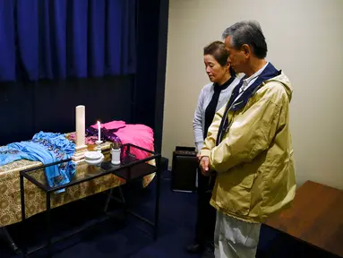 Hirokazu Hosaka (kanan) dan istrinya, Minako Hosaka mengamati peti mati ibunya di 'Corpse Hotel' di Kawasaki, Jepang, 20 April 2016. Tempat itu adalah kamar mayat yang didesain untuk menyimpan jenazah yang menunggu jadwal kremasi. (REUTERS/Thomas Peter)