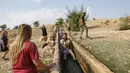 Seorang pria meluncur saat menikmati bermain air di sebuah kanal kecil di Desa Al-Auja selama perayaan keagamaan Yahudi dalam Festival Sukkot di Tepi Barat (17/10/2019). (AFP Photo/Menahem Kahana)