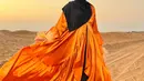 Kali ini, Tasyi tampil benar-benar seperti Arabian princess. Berlatar padang pasir, dress megah berwarna oranye yang Tasyi kenakan disempurnakan dengan hijab hitam dan aksesori emasnya. Foto: Instagram.