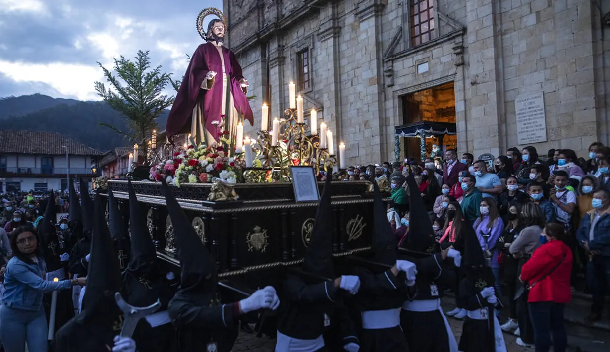 Anggota persaudaraan Nazarene membawa patung yang menggambarkan Yesus Kristus di atas kendaraan hias selama prosesi Jumat Agung di Zipaquira, Kolombia, 15 April 2022. Prosesi dan kendaraan hias keagamaan berpawai melalui jalan-jalan desa dan kota di seluruh wilayah. (AP Photo/Ivan Valencia)