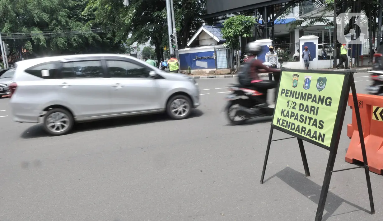 Kendaraan melintasi papan imbauan saat penindakan Pembatasan Sosial Berskala Besar (PSBB) di kawasan Menteng, Jakarta, Senin (13/4/2020). (merdeka.com/Iqbal S. Nugroho)