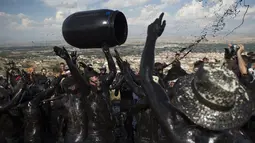 Peserta melemparkan ember berisi minyak hitam saat mengikuti Festival Tradisionlal Cascamorras di Baza, Granada, Spanyol (6/9/2019). Festival Cascamorras menggambarkan kekuatan dan kemampuan Baza untuk mempertahankan Virgen de la Piedad. (AFP Photo/Jorge Guerrero)