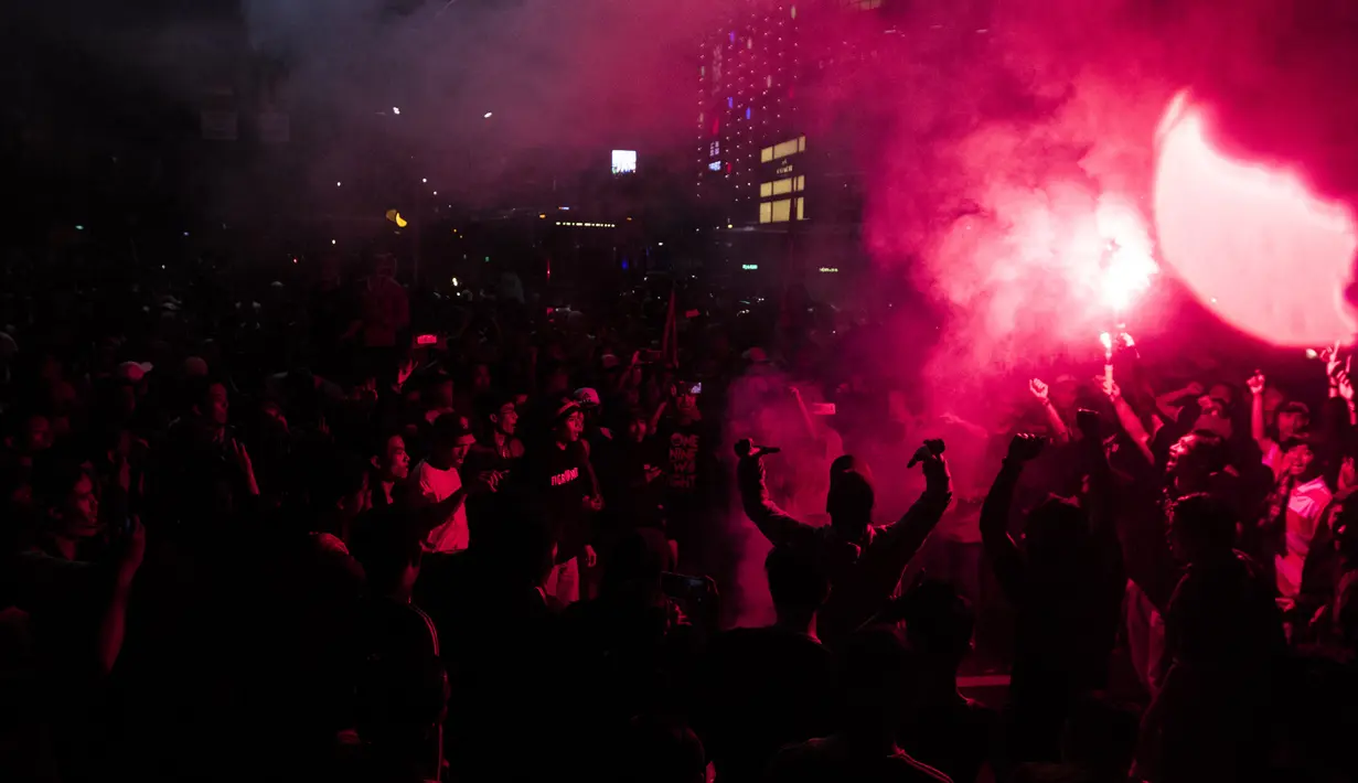 Suporter Persija Jakarta, The Jakmania, menyalakan flare saat merayakan pesta juara Liga 1 di Bundaran Hotel Indonesia, Jakarta, Minggu (9/12). Persija unggul satu poin dari PSM Makassar di puncak klasemen. (Bola.com/Vitalis Yogi Trisna)