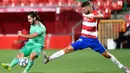 Gelandang Real Madrid, Isco menembak bola dari kawalan pemain Granada, Domingos Duarte pada pertandingan lanjutan La Liga Spanyol di stadion Nuevo Los Carmenes di Granada (13/7/2020). Madrid menang tipis 2-1 atas Granada. (AP Photo/Jose Breton)