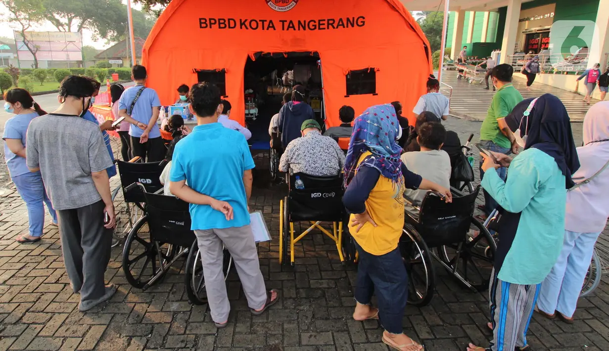 Pasien yang terpapar Covid-19 antre di luar tenda darurat yang didirikan di RSUP dr Sintanala, Kota Tangerang, Rabu (30/6/2021).  Pasien yang mengantre di luar tenda harus menunggu dengan menggunakan Kursi Roda. (Liputan6.com/Angga Yuniar)